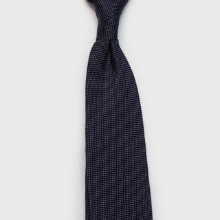 Knotted micro patterned navy blue silk tie highlighting its refined style.