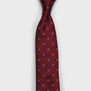 Elegant red floral grenadine tie tied in a knot, showcasing blue floral pattern.