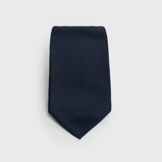 Solid dark blue silk tie with a classic six-fold design, folded flat.