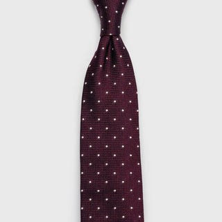 Full-length view of burgundy grenadine silk tie with white dots.